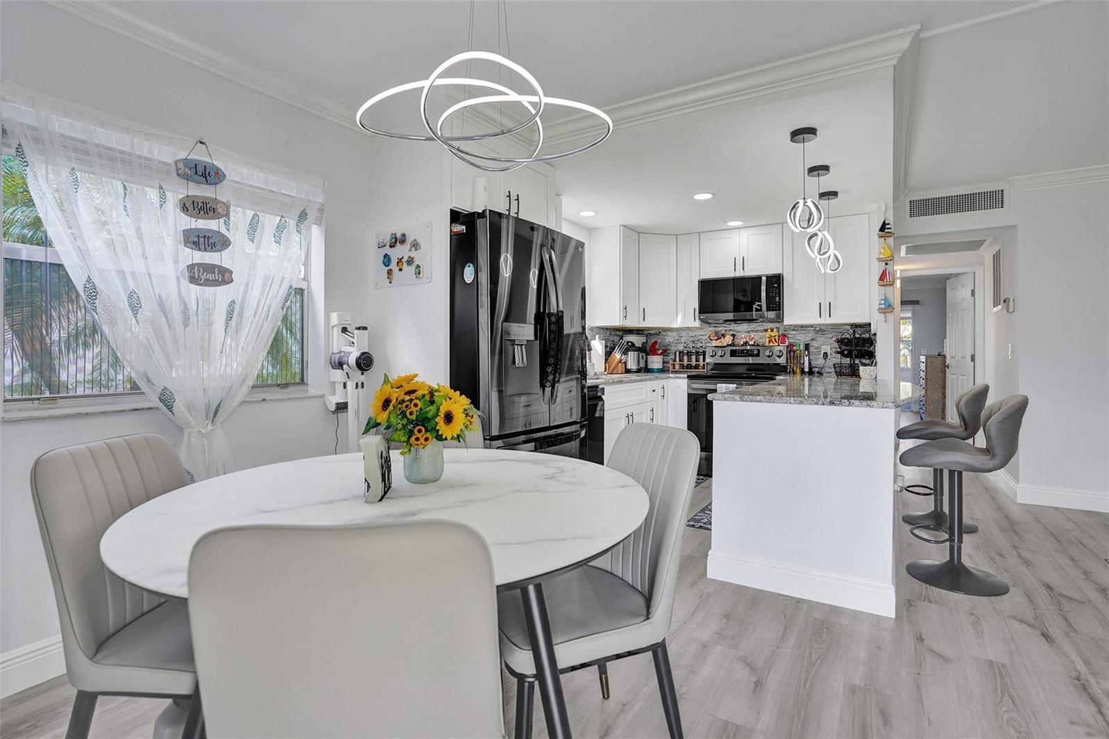 A kitchen and dining area with white cabinets, a marble-topped table, and grey chairs — 356 Brittany H # 356, Delray Beach FL 33446, DELRAY BEACH, FL