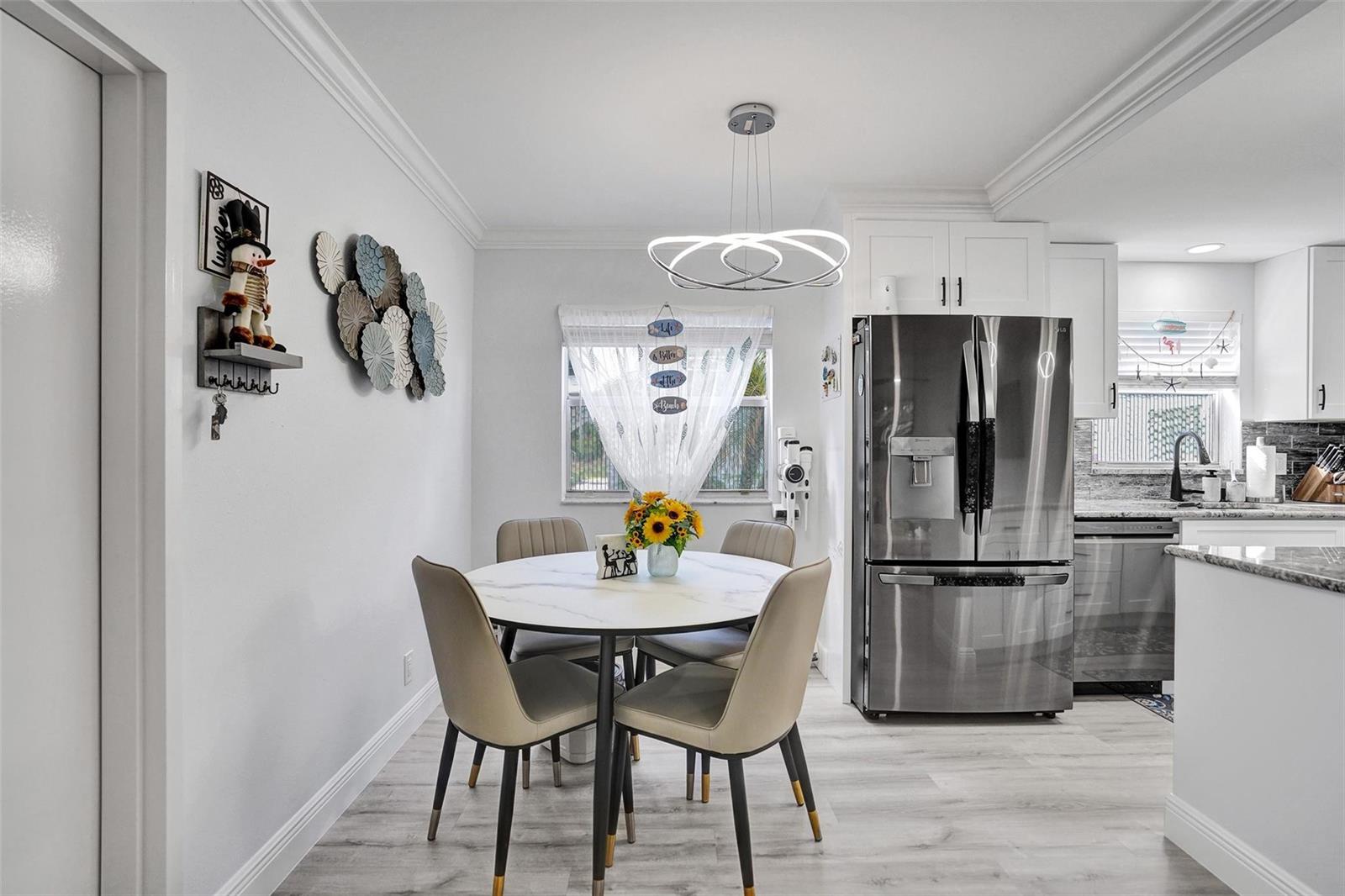 A dining area with a round marble table, four chairs, and a modern light fixture — 356 Brittany H # 356, Delray Beach FL 33446, DELRAY BEACH, FL