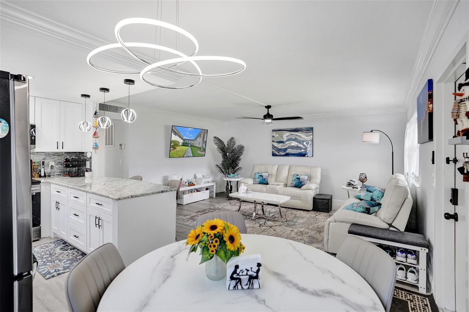 An open-concept living room and kitchen featuring white cabinetry, a marble island, and modern lighting — 356 Brittany H # 356, Delray Beach FL 33446, DELRAY BEACH, FL