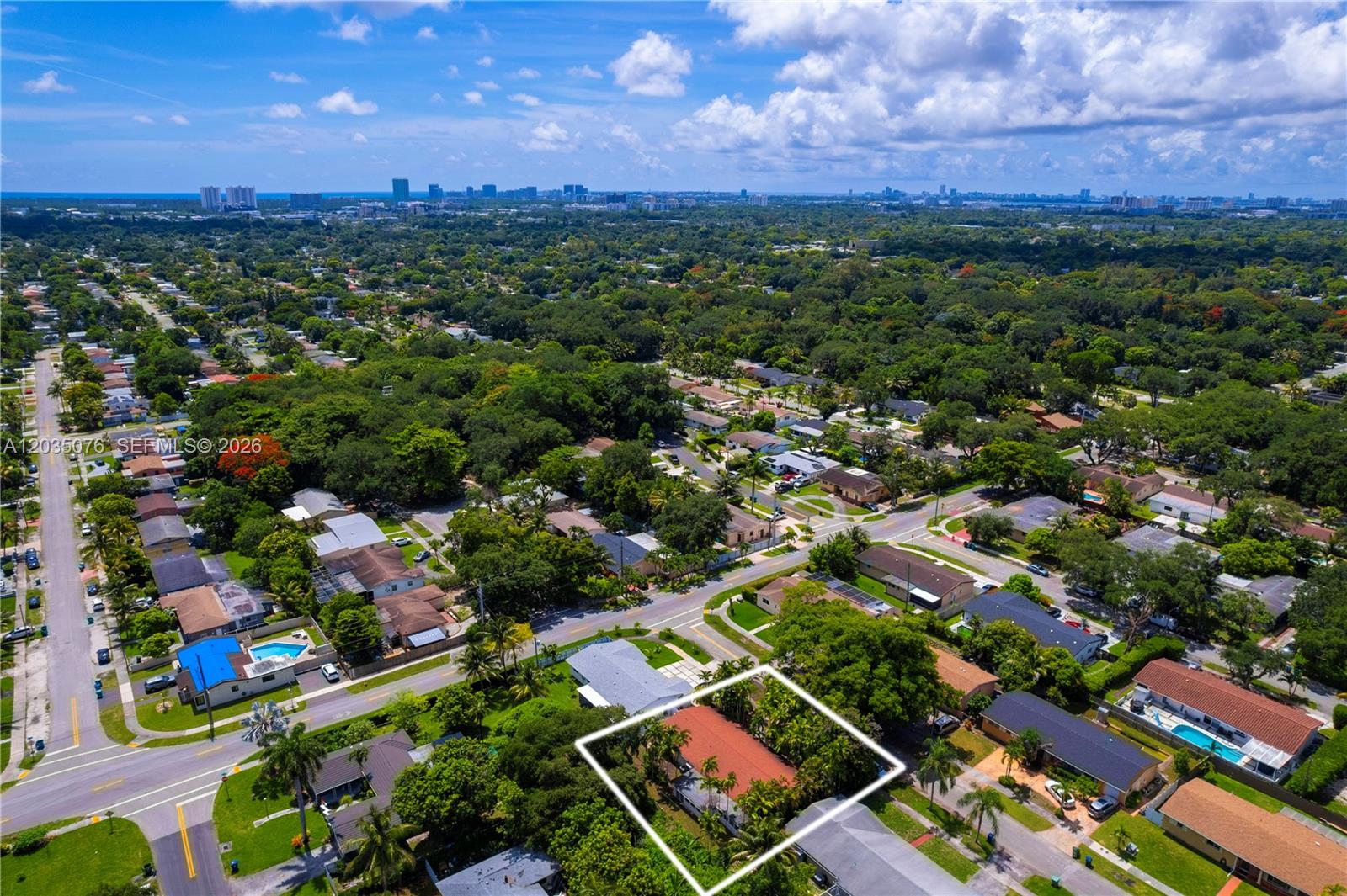 An aerial view shows a residential property with a red-roofed house surrounded by lush trees — 785 NE 155th St, Miami FL 33162, MIAMI, FL