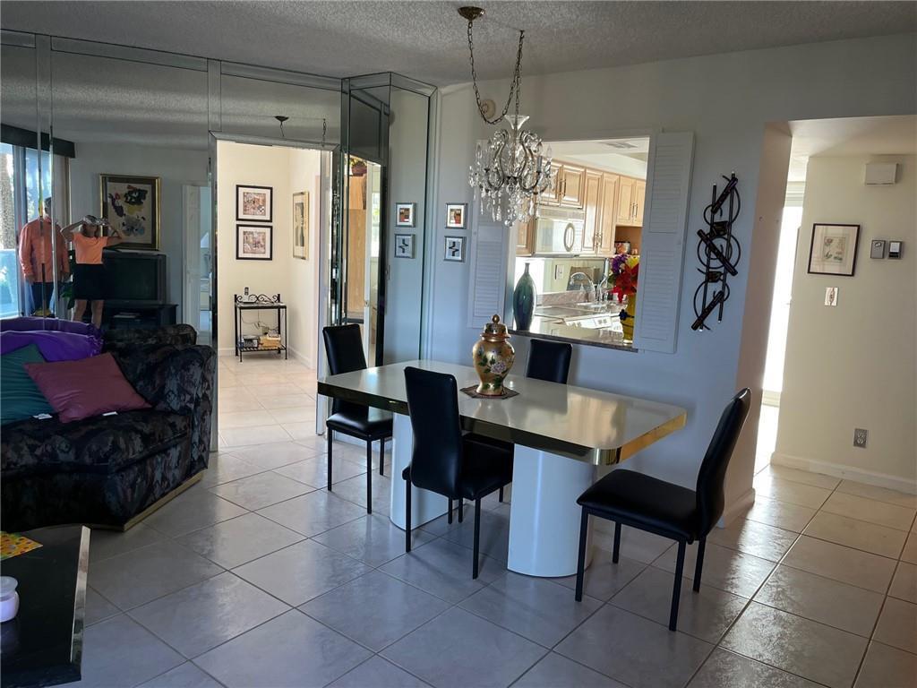 A dining area features a white table, black chairs, a crystal chandelier, and mirrored walls — 333 NE 21 Avenue # 304, Deerfield Beach FL 33441, DEERFIELD BEACH, FL