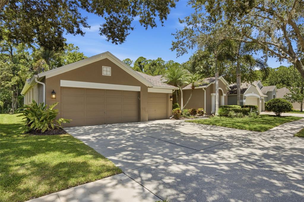 A tan single-story house with a three-car garage and a concrete driveway — 10212 NEWINGTON PLACE, TAMPA, FL