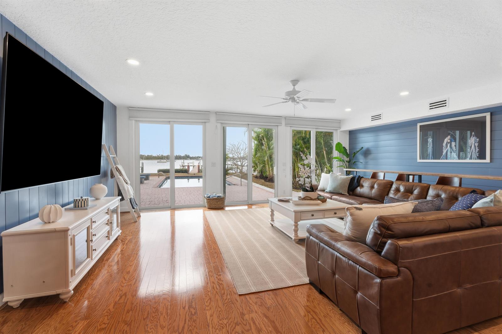 A living room features blue shiplap walls, a brown leather sectional, and sliding glass doors — 114 S Lake Drive, Lantana FL 33462, LANTANA, FL
