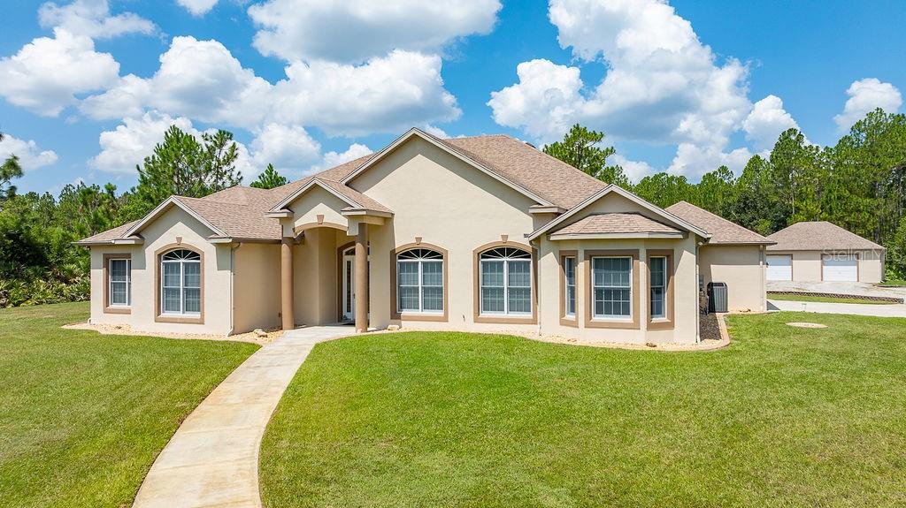 A single-story beige house with a tan shingled roof, front walkway, and detached garage — 147 ASHBY COVE LANE, NEW SMYRNA BEACH, FL