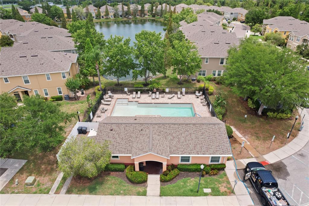 An aerial view shows a community swimming pool and clubhouse next to a small lake — 9107 MOONLIT MEADOWS LOOP, RIVERVIEW, FL