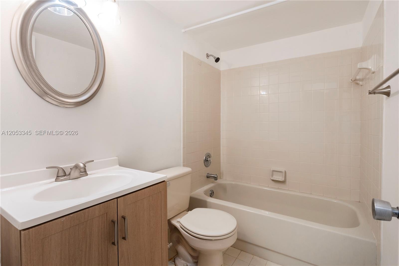 A bathroom features a vanity, toilet, and a bathtub with beige tiled walls — 20260 NE 3rd Ct # 2, Miami FL 33179, MIAMI, FL