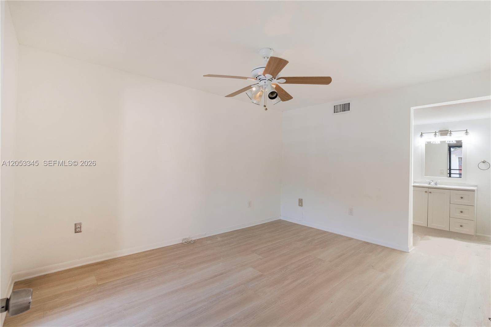 An empty bedroom with light wood-look flooring, a ceiling fan, and an attached bathroom — 20260 NE 3rd Ct # 2, Miami FL 33179, MIAMI, FL