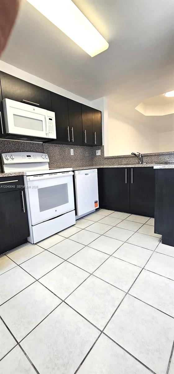 A kitchen features dark wood cabinets, white appliances, and light-colored tile flooring — 14169 SW 120th Ct # 13, Miami FL 33186, MIAMI, FL