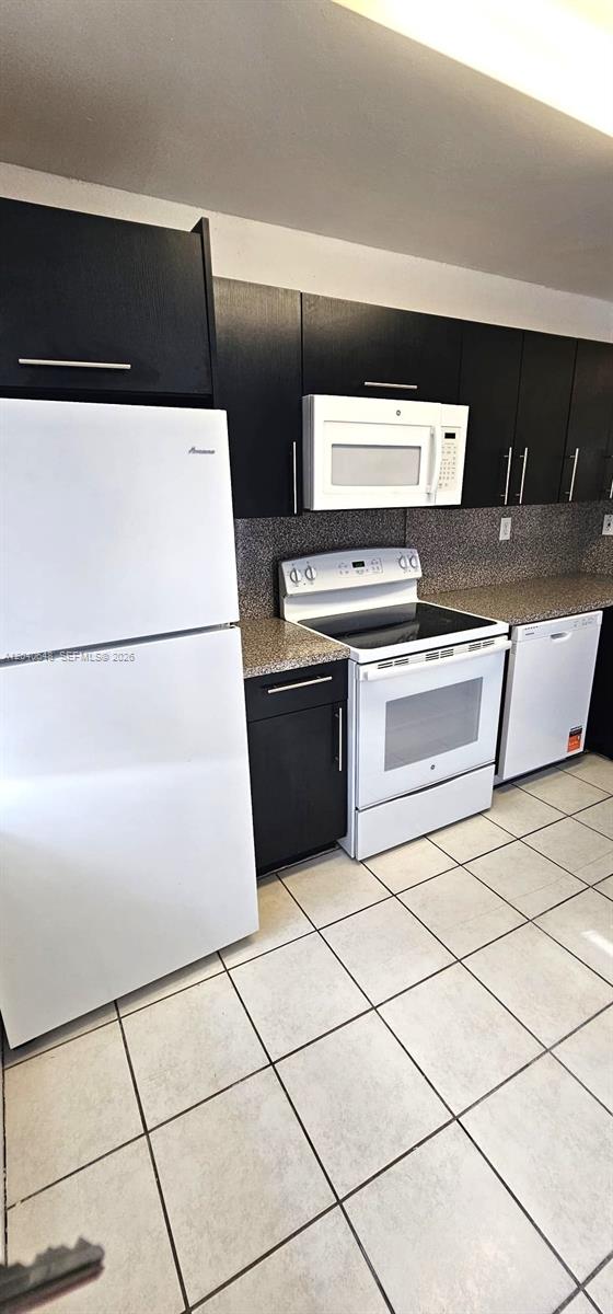A kitchen features black cabinets, white appliances, speckled countertops, and light-colored floor tiles — 14169 SW 120th Ct # 13, Miami FL 33186, MIAMI, FL
