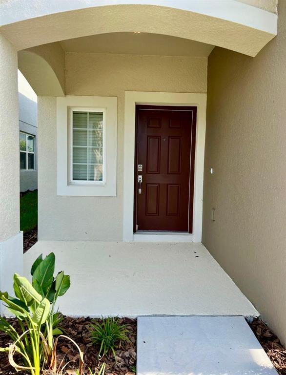 A covered entryway features a brown front door, a single window, and a concrete porch — 4553 TEOLI COURT, KISSIMMEE, FL