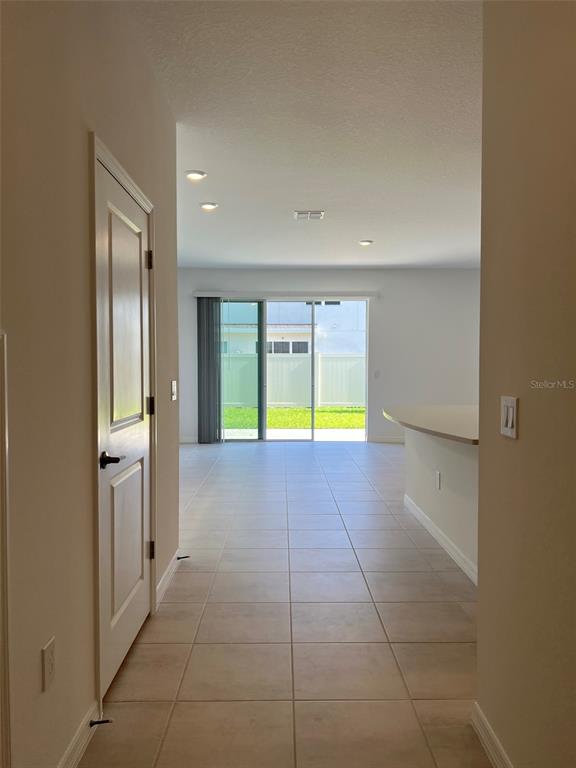 A tiled hallway leads to an open living area with sliding glass doors to a yard — 4553 TEOLI COURT, KISSIMMEE, FL