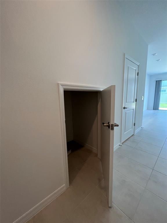 A small, open storage closet with a white door is set into a hallway wall — 4553 TEOLI COURT, KISSIMMEE, FL