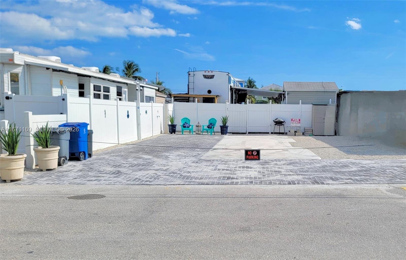 A paved outdoor parking area features a white vinyl fence, two chairs, and potted plants — 325 Calusa St 376, Key Largo FL 33037, KEY LARGO, FL