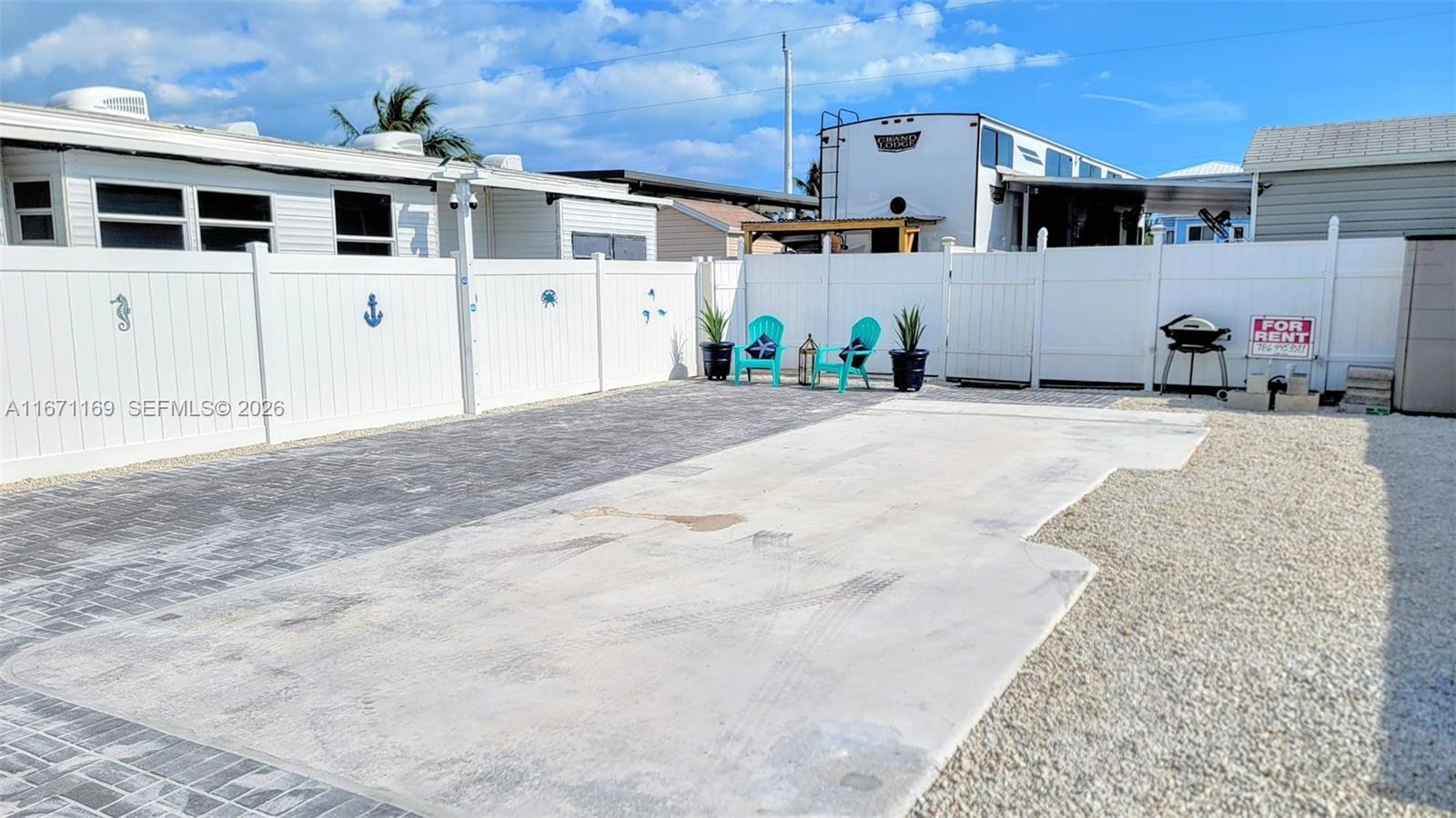 An outdoor patio area features a concrete pad, paved section, white vinyl fencing, and chairs — 325 Calusa St 376, Key Largo FL 33037, KEY LARGO, FL