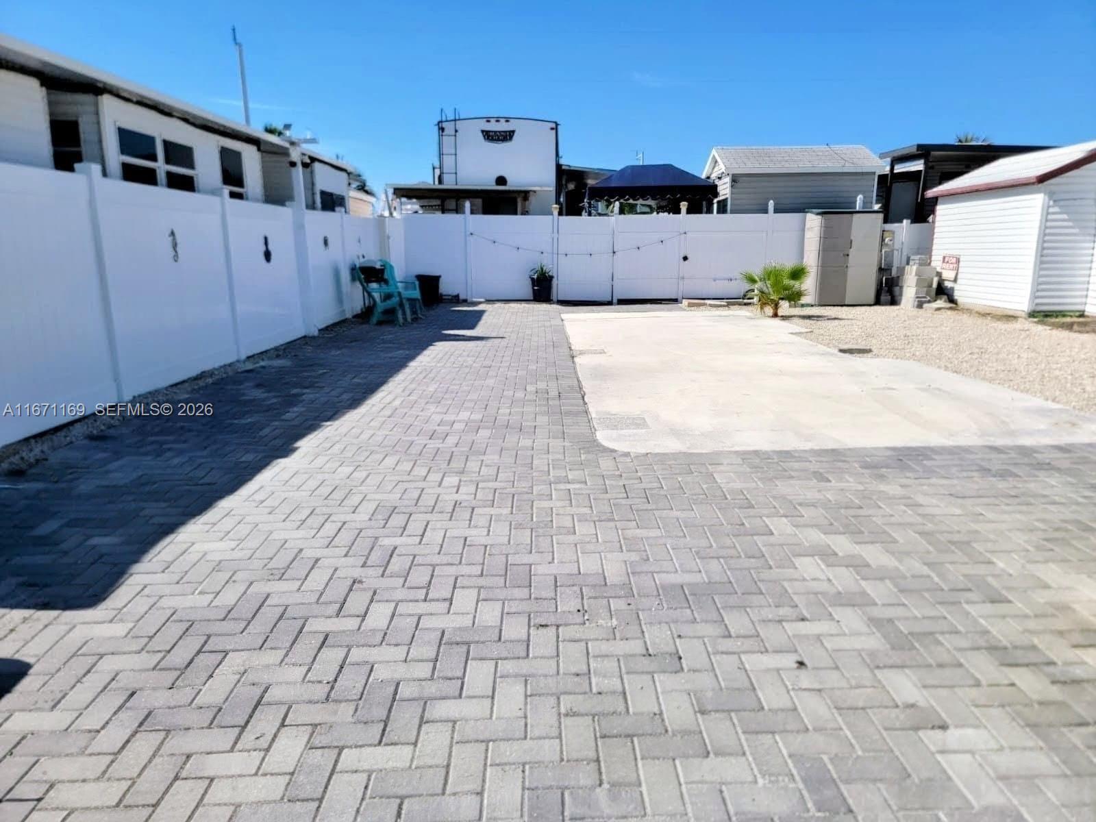 A paved patio area features a concrete pad, white vinyl fencing, and a small palm tree — 325 Calusa St 376, Key Largo FL 33037, KEY LARGO, FL