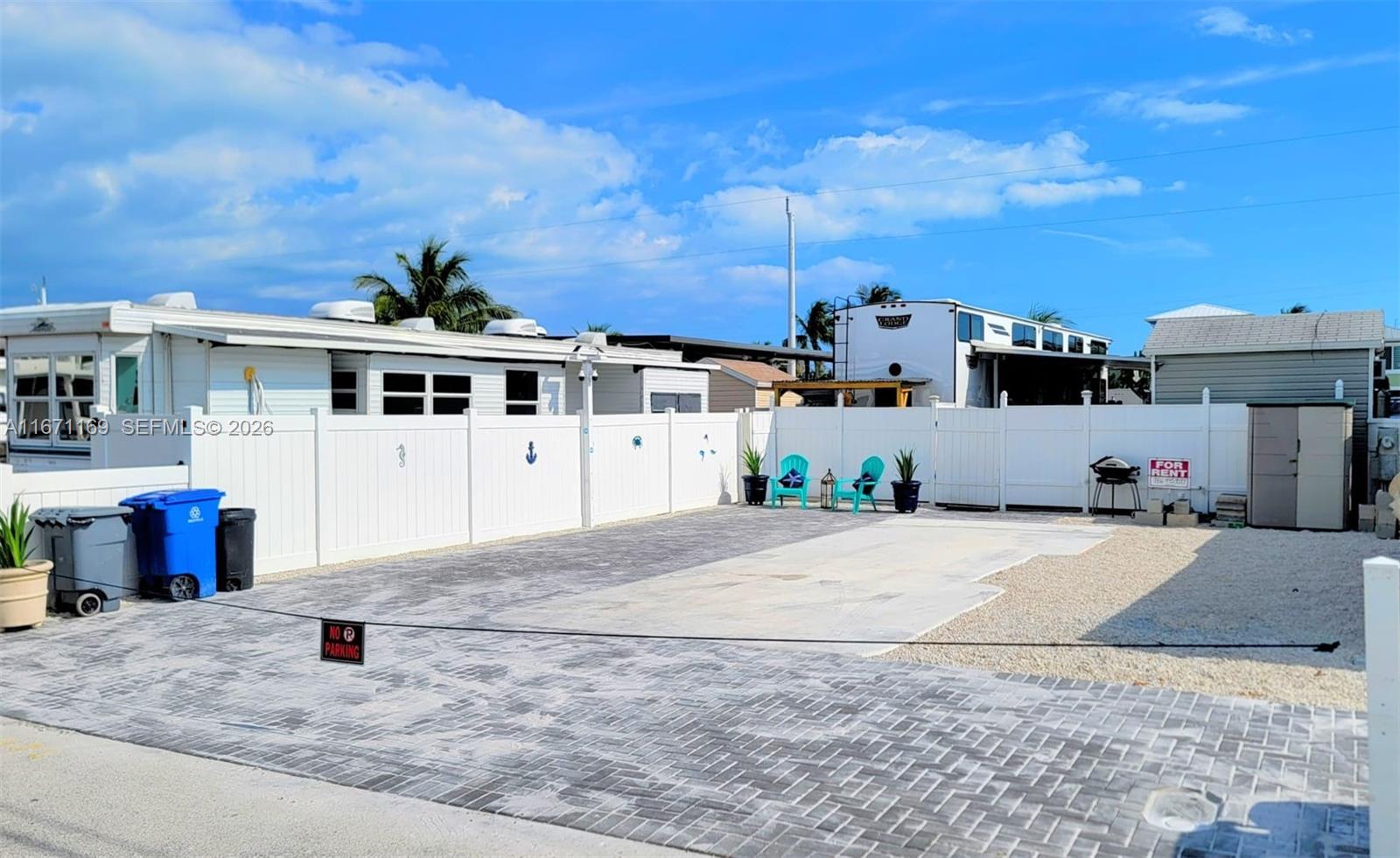 A paved driveway sits in front of a white fence with two turquoise chairs — 325 Calusa St 376, Key Largo FL 33037, KEY LARGO, FL