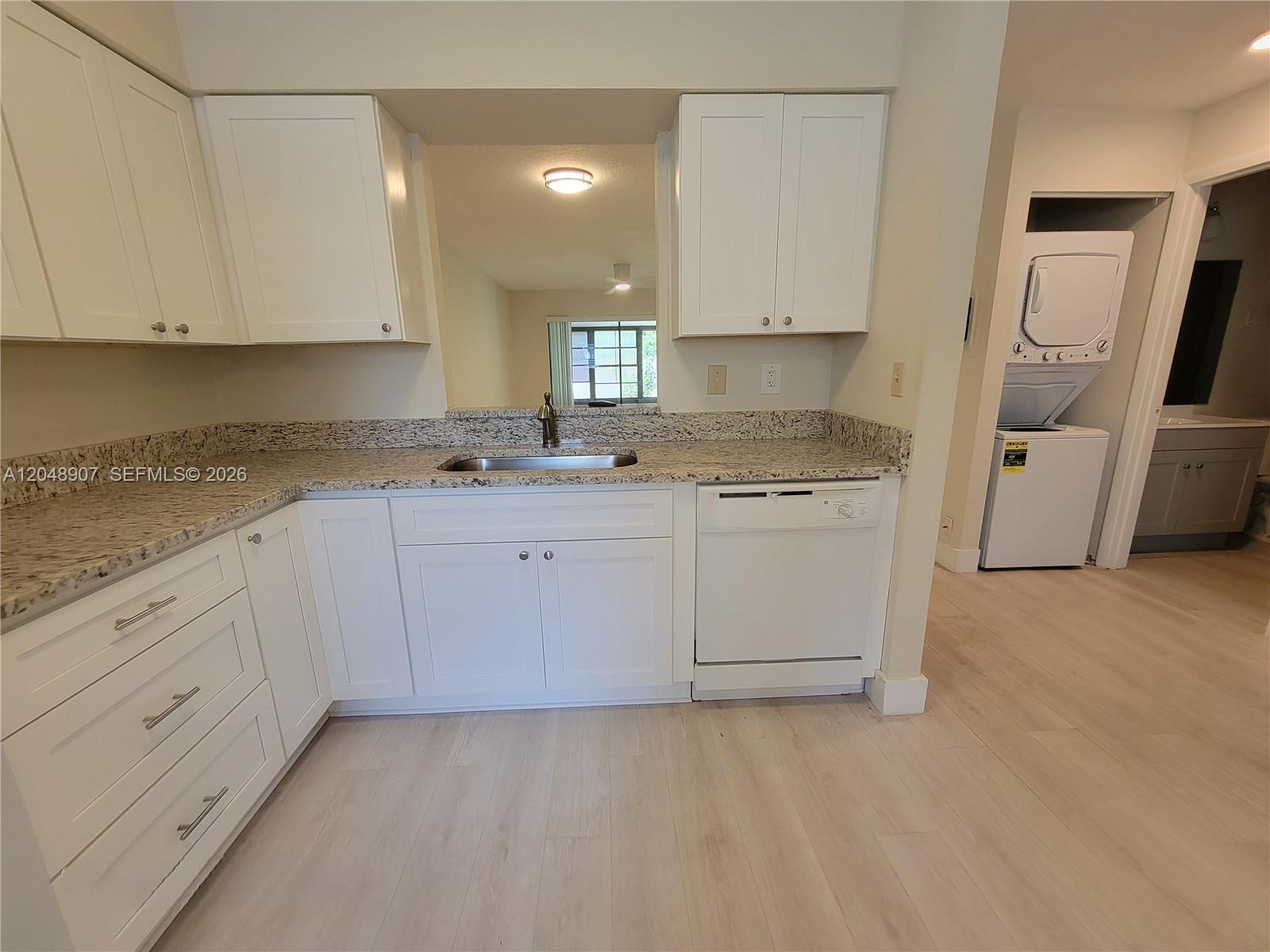A kitchen features white cabinets, granite countertops, a stainless steel sink, and a dishwasher — 6014 Indrio Rd # 3, Fort Pierce FL 34951, FORT PIERCE, FL