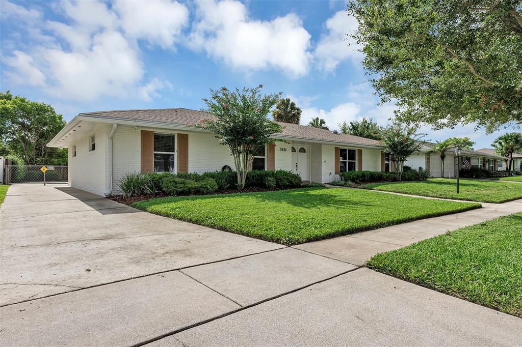 A single-story white brick house with a concrete driveway and a green front lawn — 3021 BRANDYWINE DRIVE, ORLANDO, FL