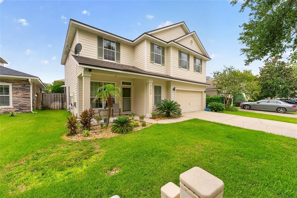A two-story house with beige siding, a front porch, and a two-car garage — 8206 NW 52ND STREET, GAINESVILLE, FL