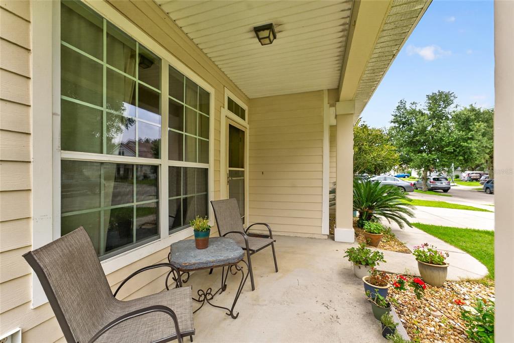A covered front porch features two chairs, a small table, and several potted plants — 8206 NW 52ND STREET, GAINESVILLE, FL