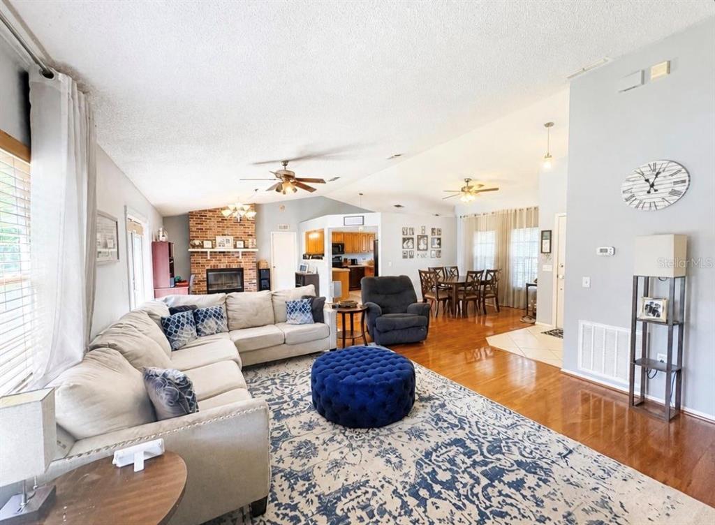 A living room with a sectional sofa, blue ottoman, fireplace, and adjacent dining area — 561 ASTORIA DRIVE, DELAND, FL