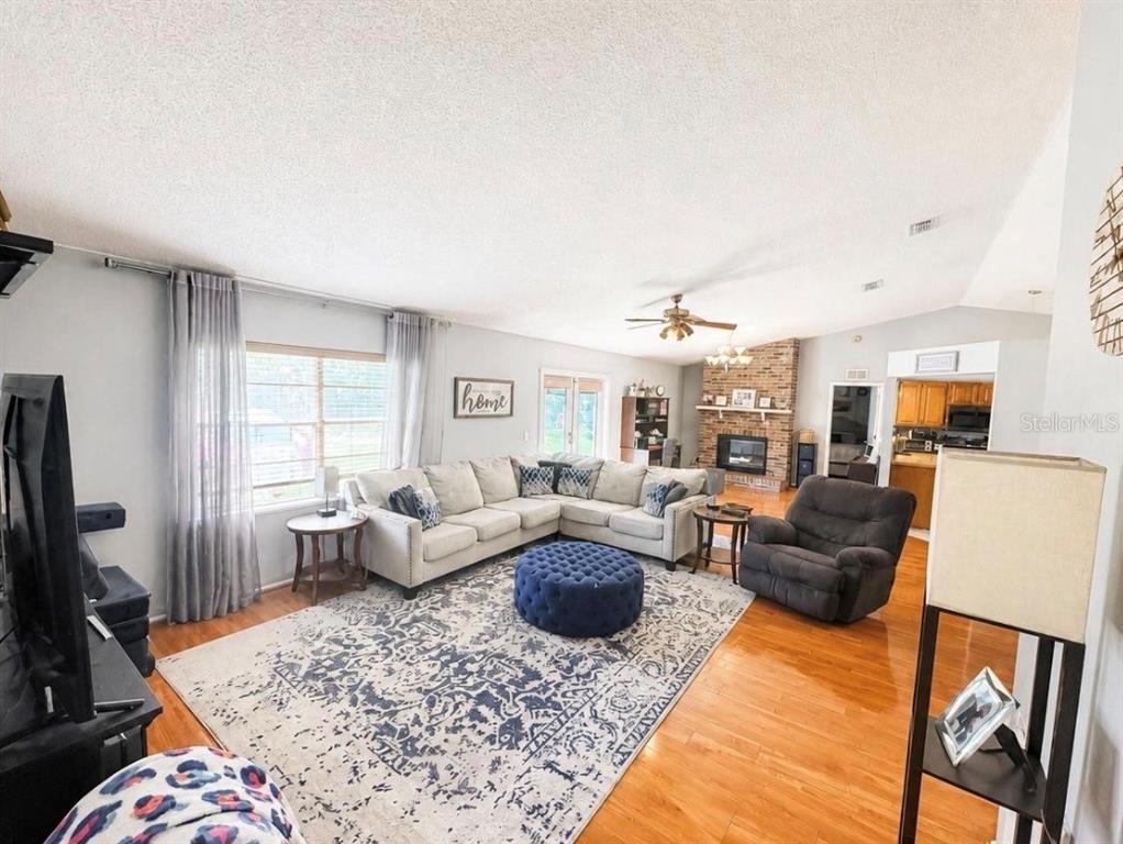 A living room features a sectional sofa, blue ottoman, fireplace, and hardwood flooring — 561 ASTORIA DRIVE, DELAND, FL