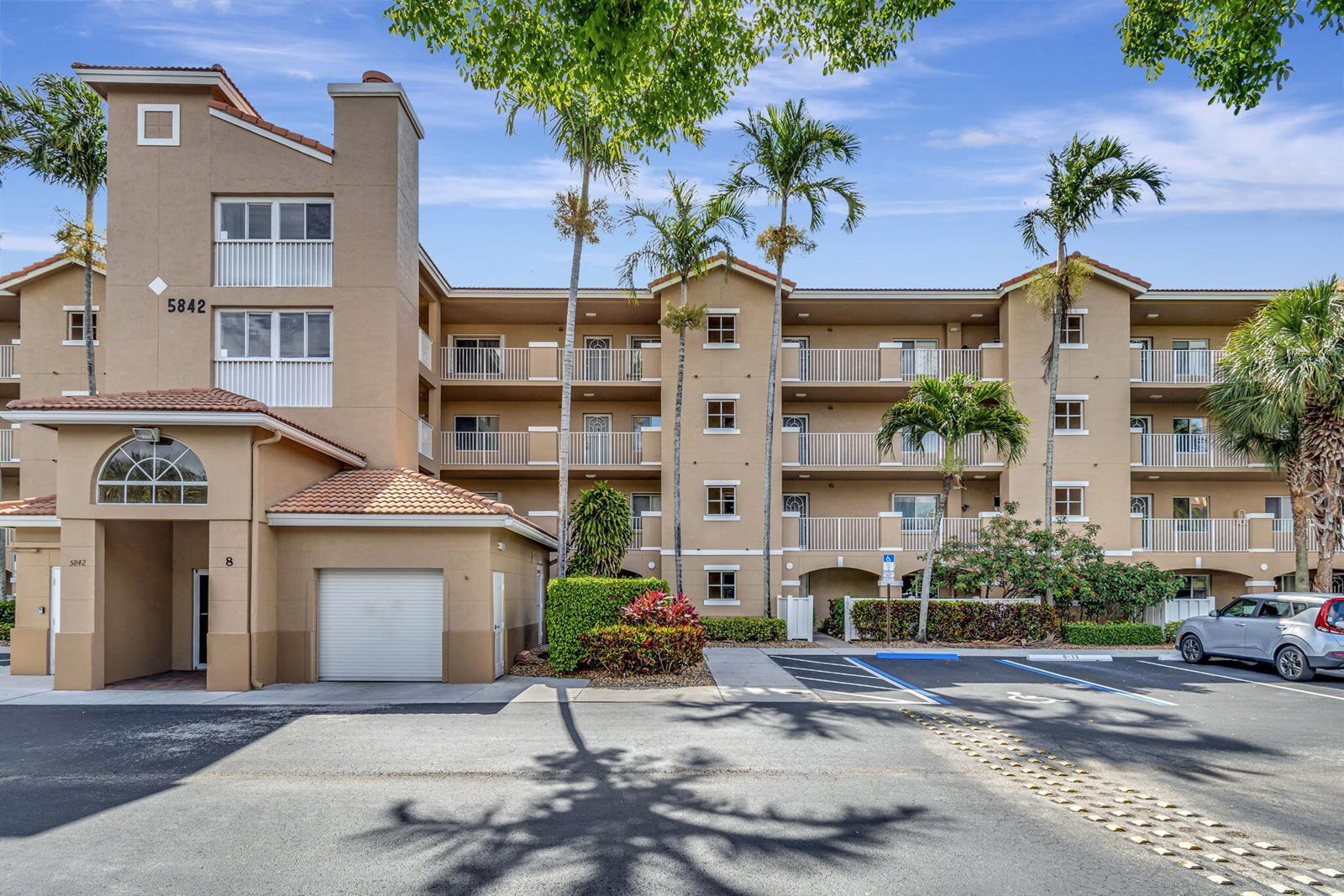 A multi-story tan apartment building features balconies, a garage, and a parking lot — 5842 Crystal Shores Drive # 105, Boynton Beach FL 33437, BOYNTON BEACH, FL