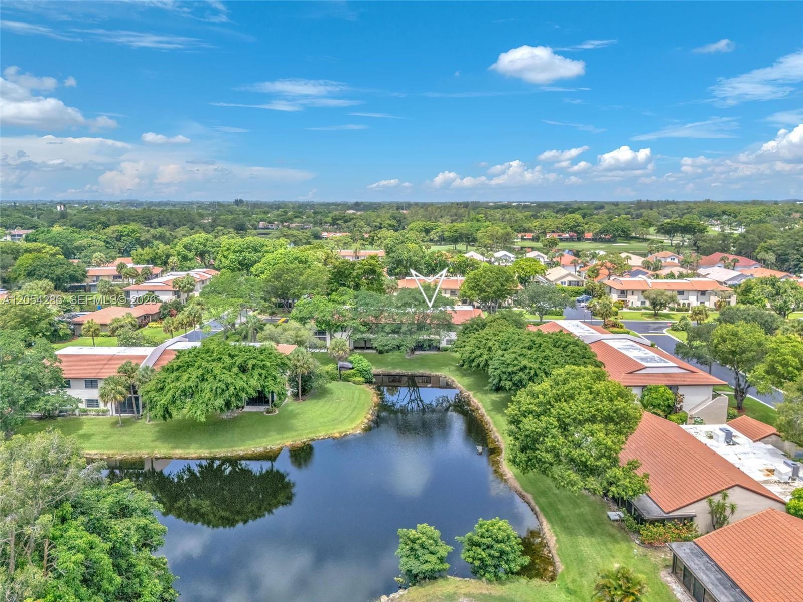 An aerial view shows a pond surrounded by residential buildings with terracotta roofs and trees — 21698 Cypress Rd # 44D, Boca Raton FL 33433, BOCA RATON, FL