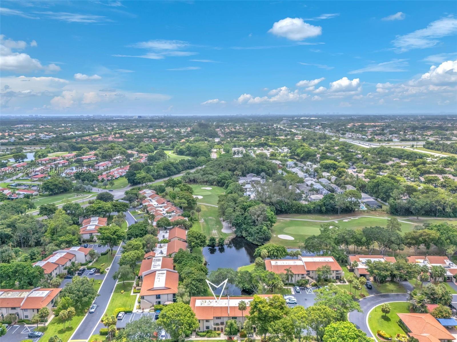 An aerial view shows a residential complex with red-tiled roofs near a pond and golf course — 21698 Cypress Rd # 44D, Boca Raton FL 33433, BOCA RATON, FL