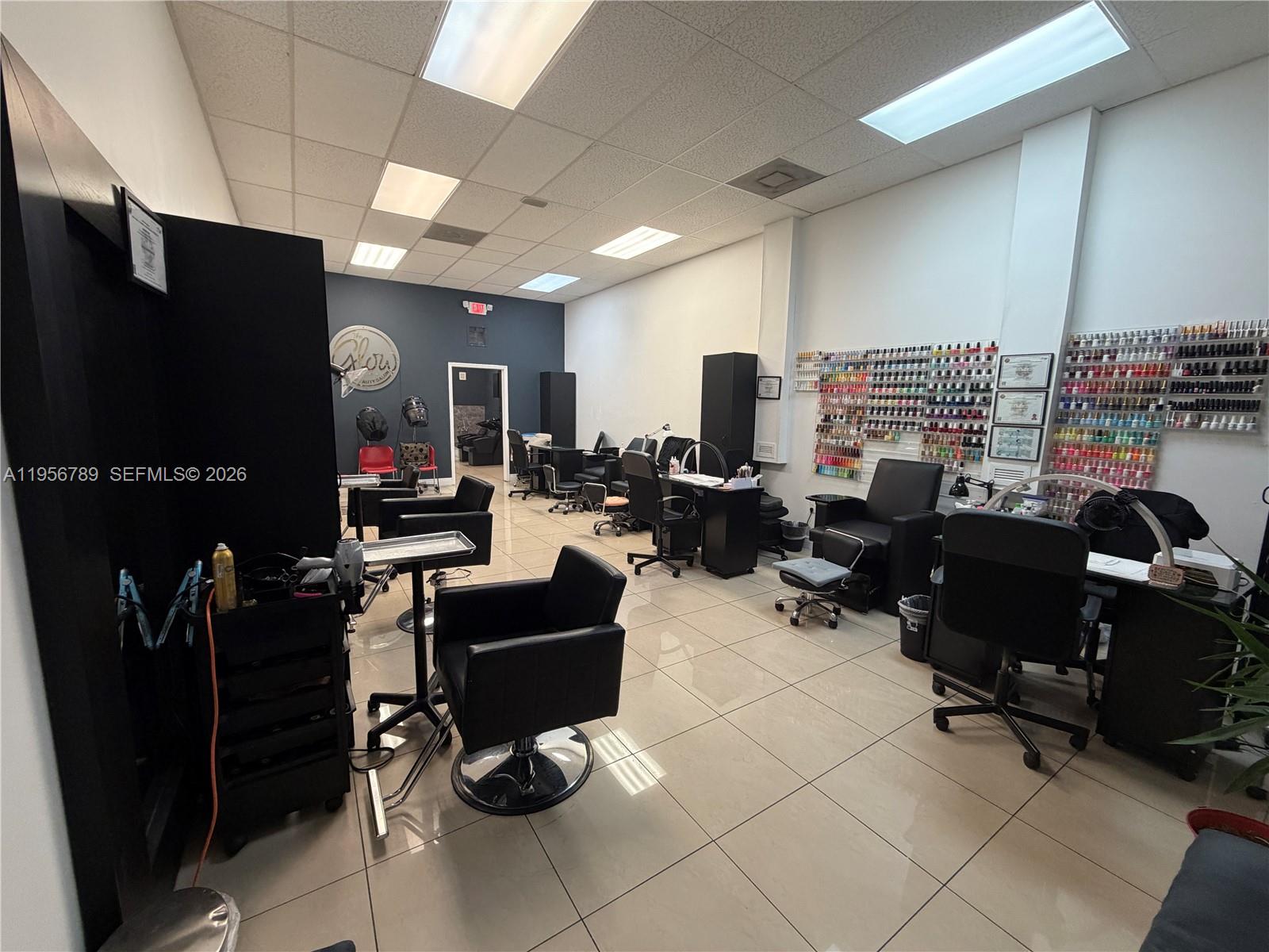 A salon interior features multiple styling chairs, nail stations, and a wall of nail polish — 18505 NW 75th Pl, Hialeah FL 33015, HIALEAH, FL