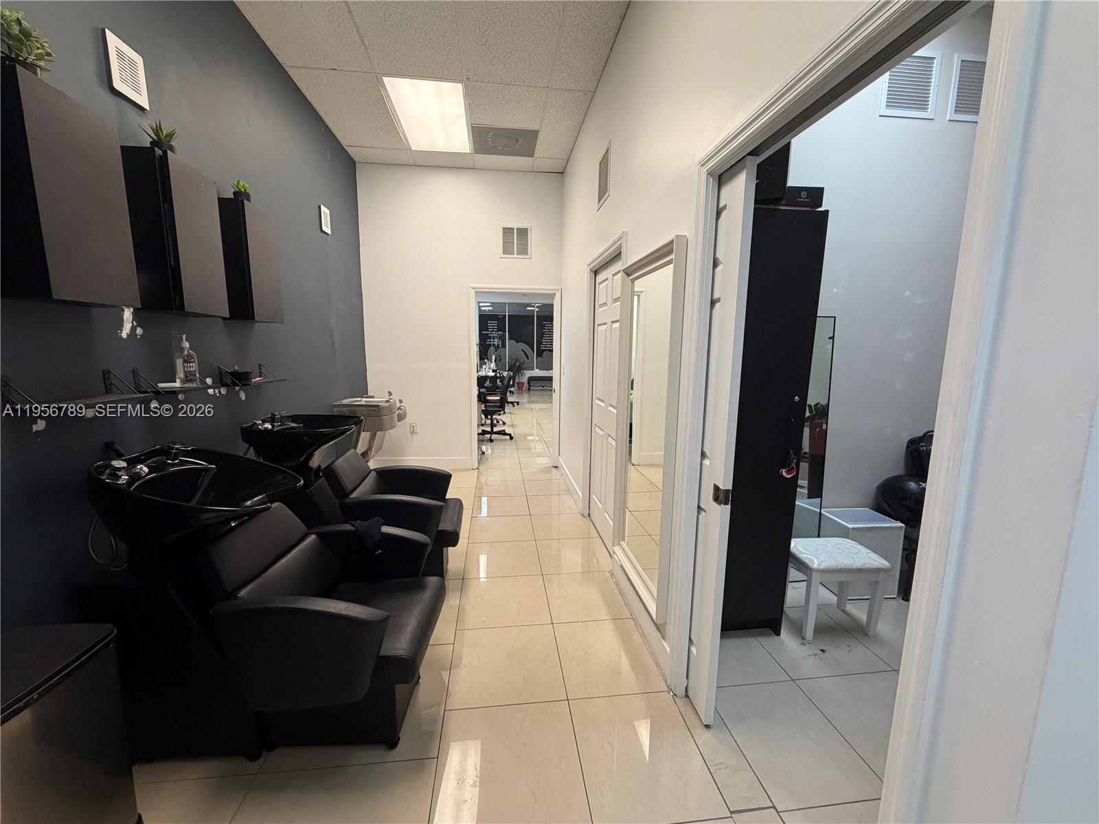 A hair salon features two black shampoo stations, tiled flooring, and an adjacent treatment room — 18505 NW 75th Pl, Hialeah FL 33015, HIALEAH, FL