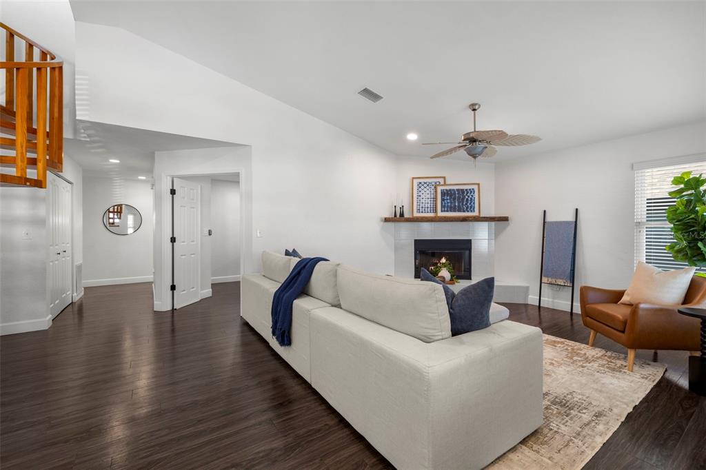 A living room features a white sofa, a fireplace, dark wood floors, and a ceiling fan — 247 126TH AVENUE, TREASURE ISLAND, FL