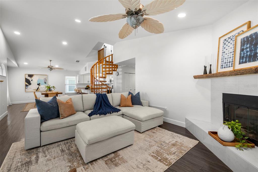 A living room features a sectional sofa, a spiral staircase, and a fireplace with mantle — 247 126TH AVENUE, TREASURE ISLAND, FL