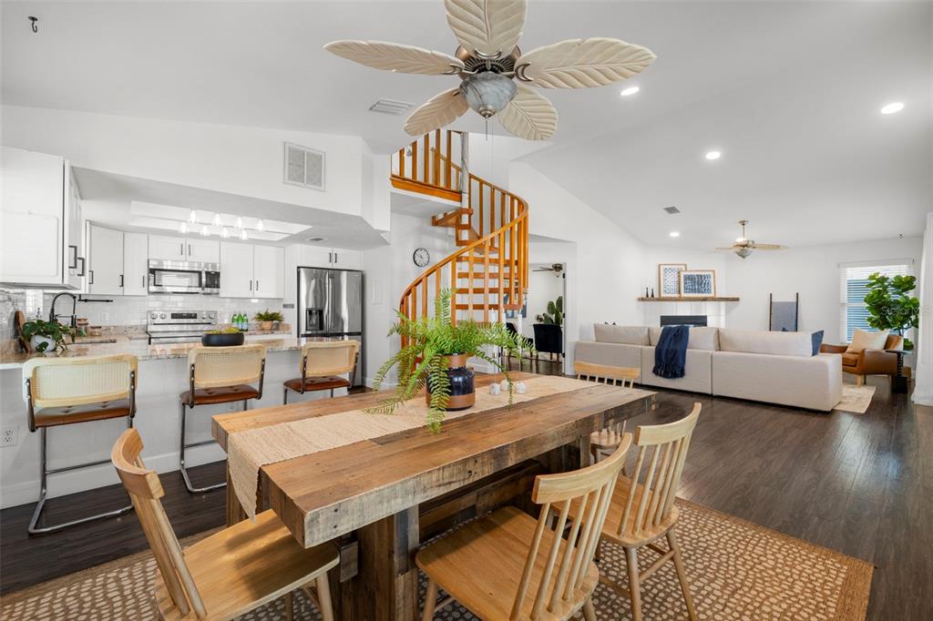 An open-concept living area features a wooden dining table, spiral staircase, and modern kitchen — 247 126TH AVENUE, TREASURE ISLAND, FL
