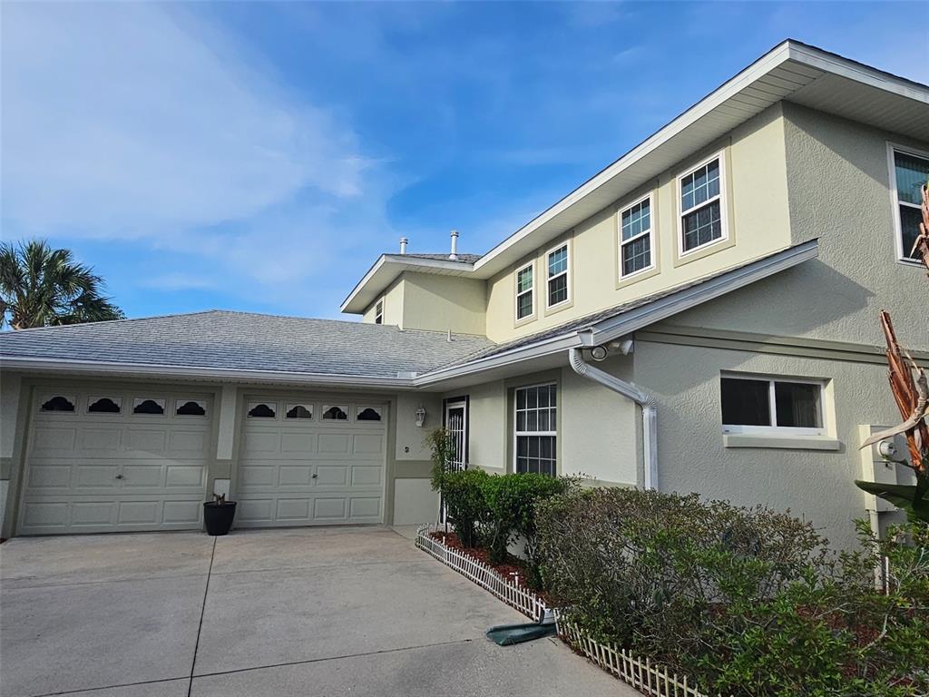 A two-story house with a beige exterior, two garage doors, and a concrete driveway — 5351 AURORA DRIVE, LEESBURG, FL