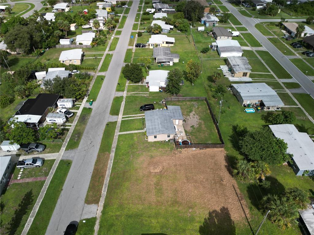 An aerial view shows a residential neighborhood with a house and a large vacant lot — 3420 CROTON TERRACE, PORT CHARLOTTE, FL