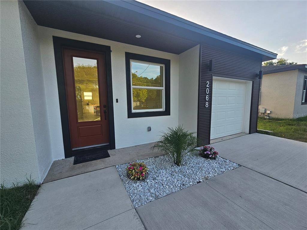 The exterior of a modern house features a red front door, white walls, and a garage — 2068 DIXIE AVE, SANFORD, FL