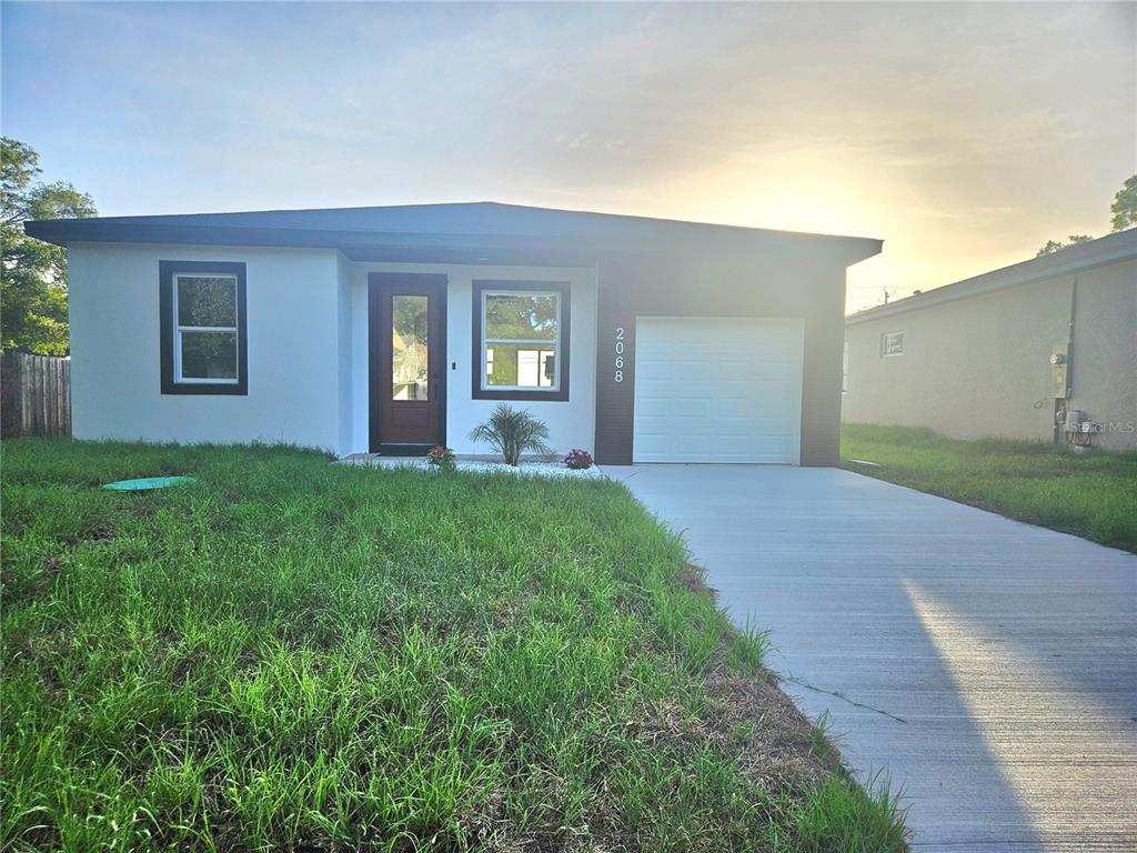 A single-story house with a white exterior, dark trim, and a one-car garage — 2068 DIXIE AVE, SANFORD, FL