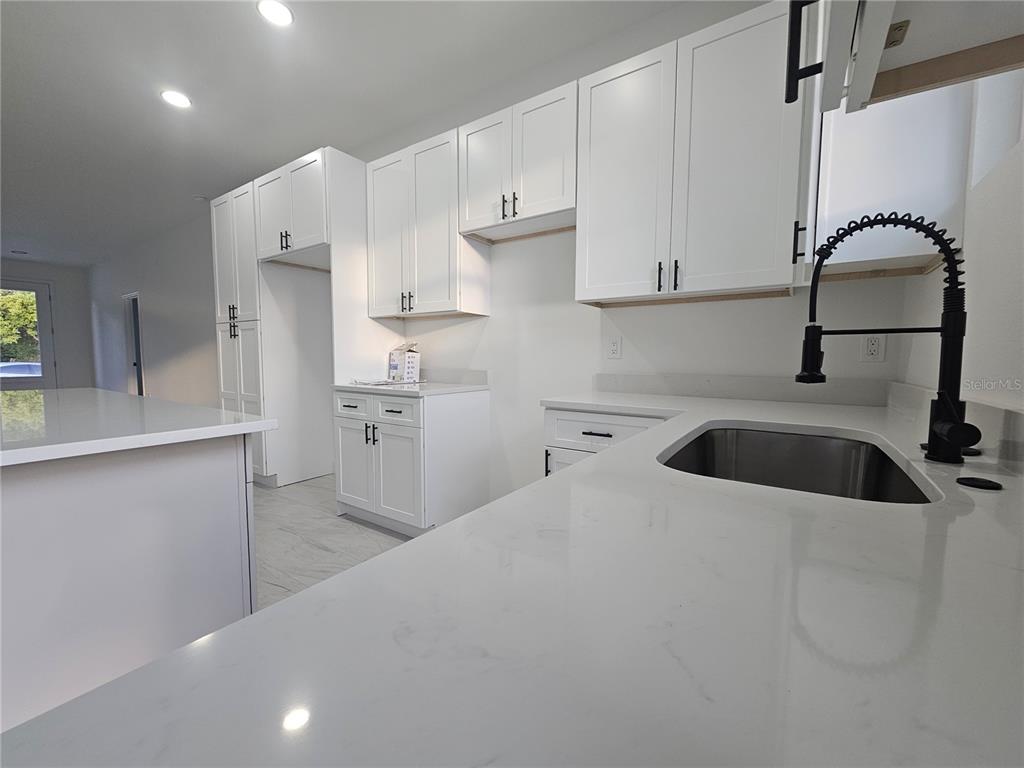 A modern kitchen features white shaker cabinets, quartz countertops, and a black gooseneck faucet — 2068 DIXIE AVE, SANFORD, FL