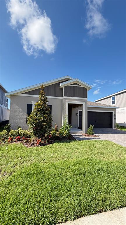 A single-story house with a tan stucco exterior, dark garage door, and a front lawn — 4585 GOLDEN KNIGHT BOULEVARD, KISSIMMEE, FL