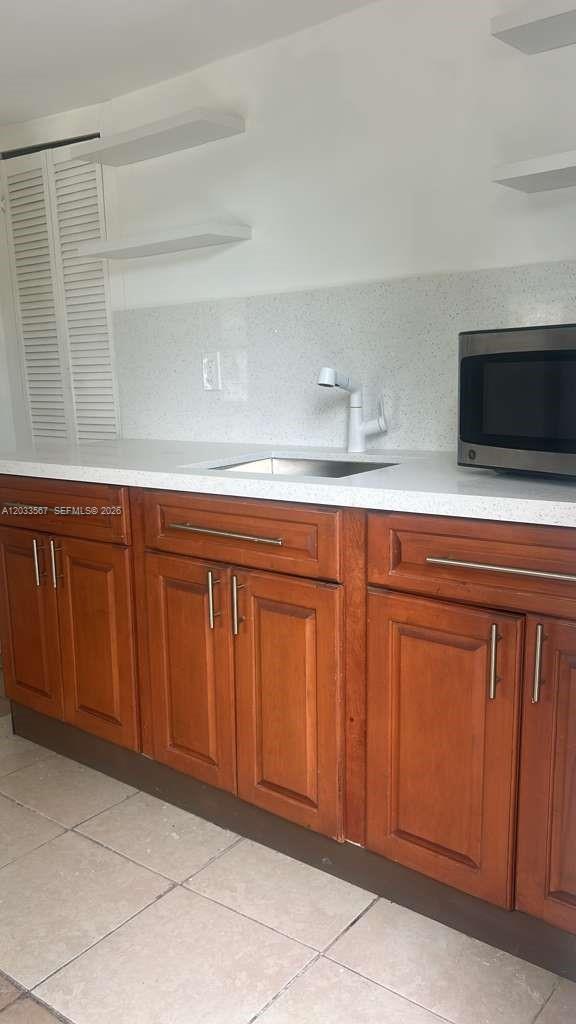 A kitchen features wooden cabinets, a white countertop, a sink, and floating shelves — 2467 NW 103rd St # 1, Miami FL 33147, MIAMI, FL