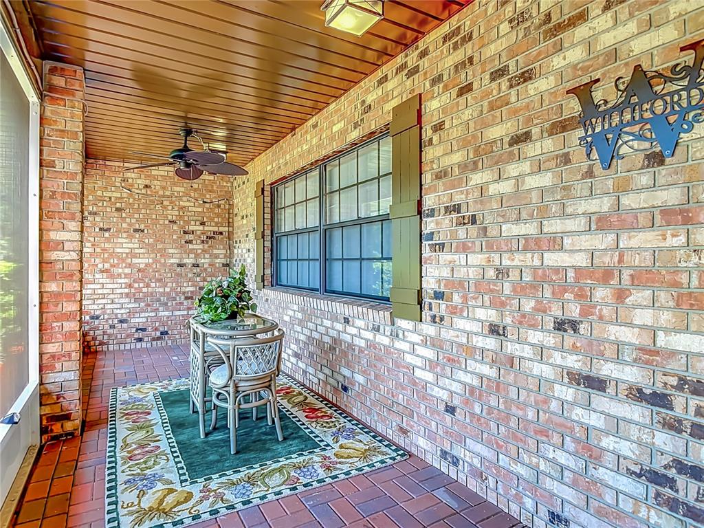 A covered brick patio features a small bistro set, a ceiling fan, and decorative shutters — 17819 PALM STREET, UMATILLA, FL