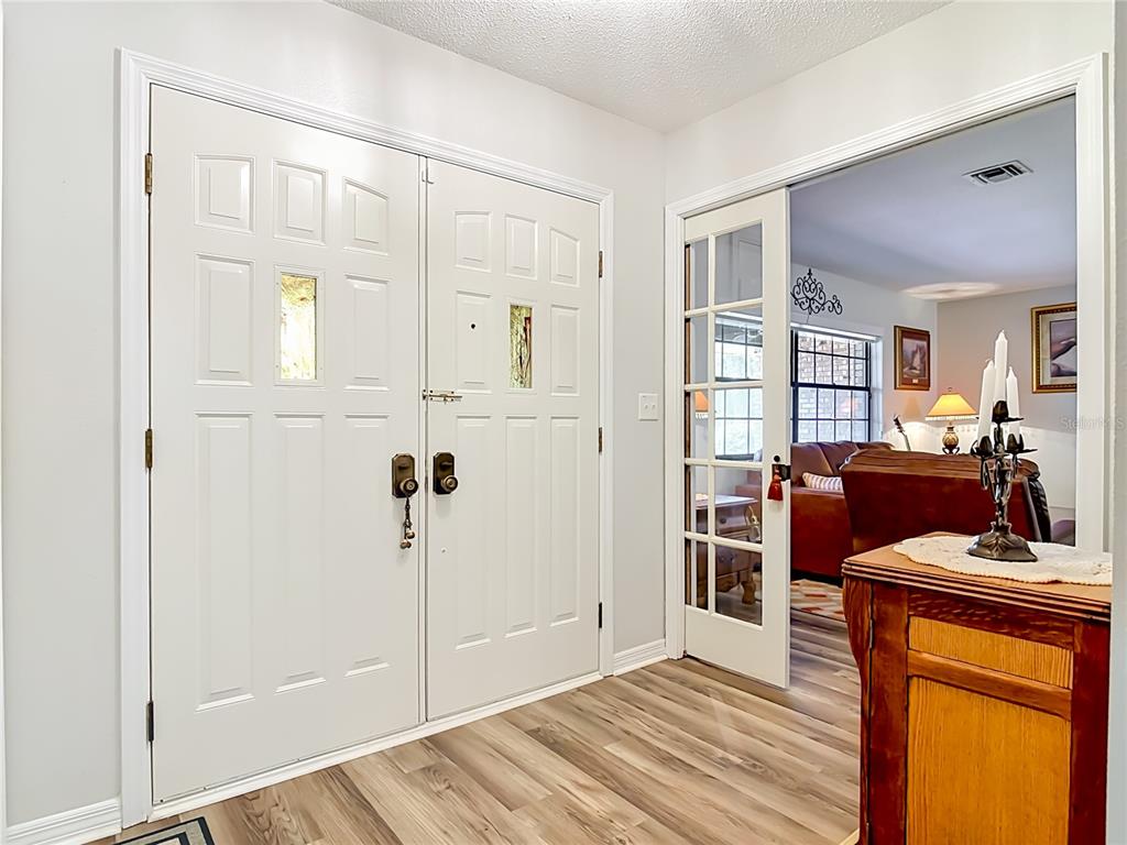 An entryway features white double front doors, wood-look flooring, and a glass-paned sliding door — 17819 PALM STREET, UMATILLA, FL