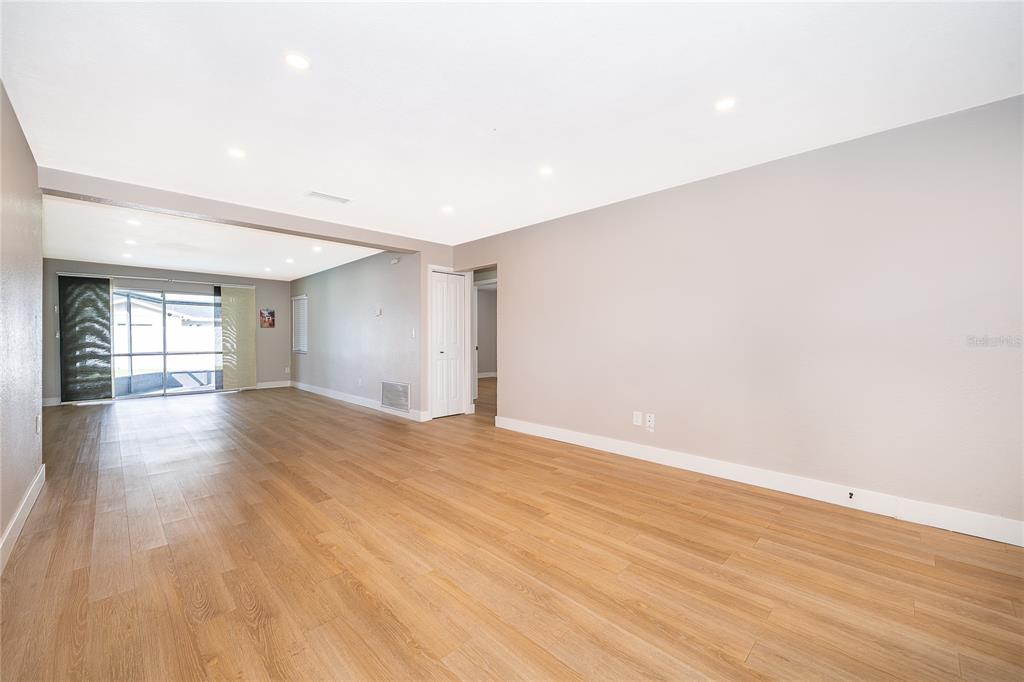 An empty living area with light wood-look flooring, recessed lighting, and a sliding glass door — 4522 FETROW DRIVE, ORLANDO, FL