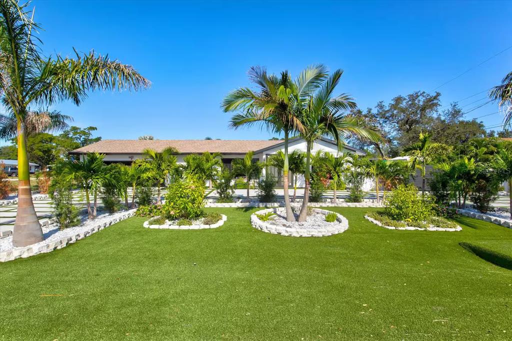 A single-story house with a manicured lawn, palm trees, and stone-bordered landscaping — 6612 9TH AVENUE NW, BRADENTON, FL