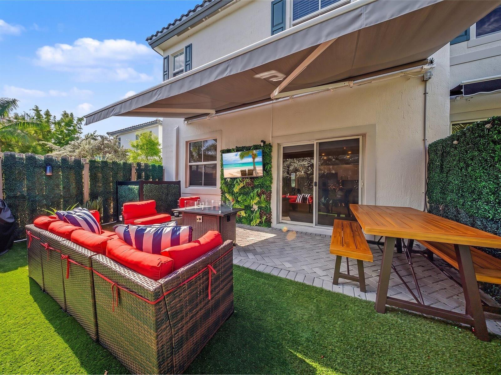 A patio features a retractable awning, outdoor furniture, a fire pit, and a wall-mounted television — 11968 NW 47th Manor, Coral Springs FL 33076, CORAL SPRINGS, FL
