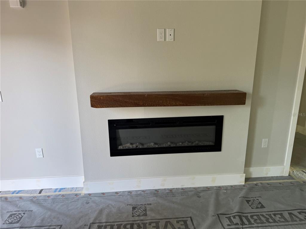 A wall-mounted electric fireplace sits below a wooden mantel in a room under construction — 62 EMERSON DRIVE, PALM COAST, FL