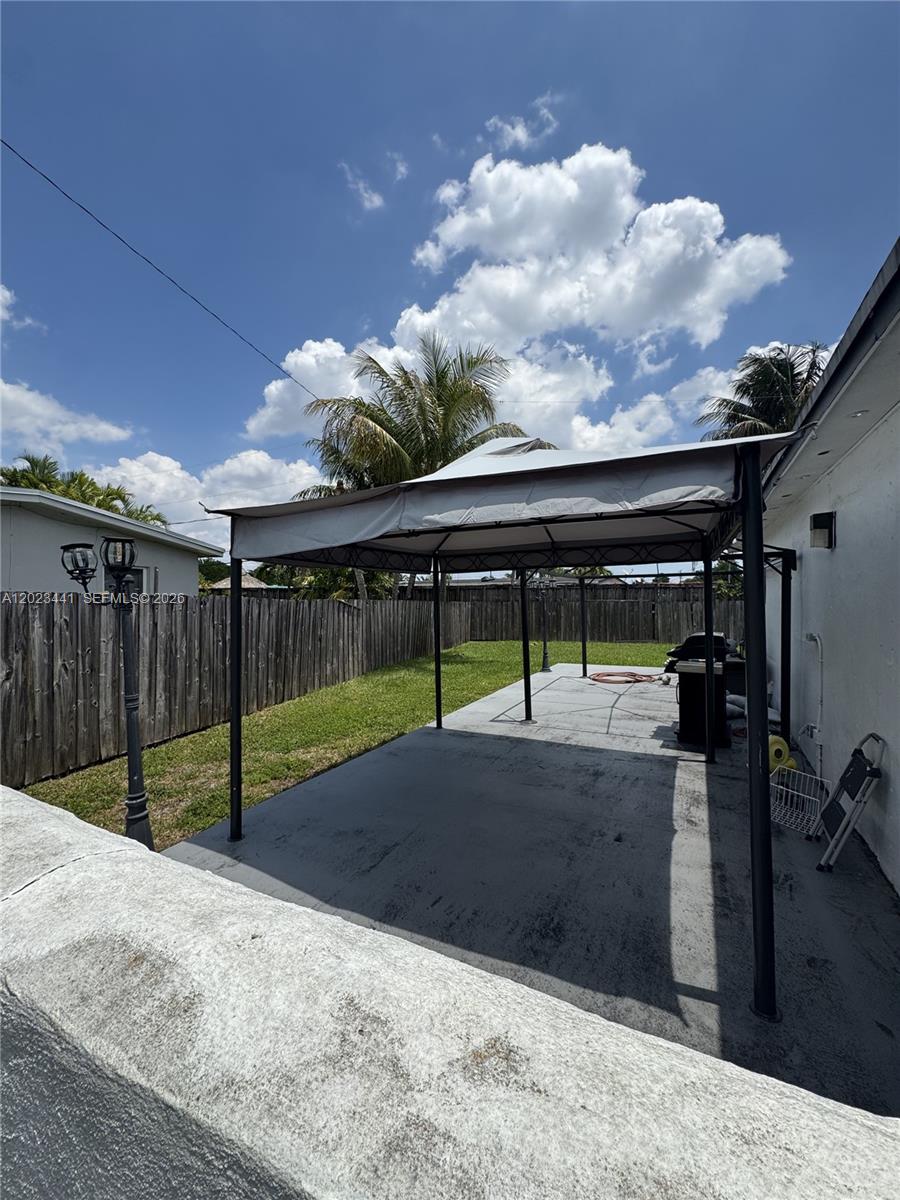 A gray metal gazebo stands on a concrete patio in a fenced backyard — 5701 SW 117th Ave, Miami FL 33183, MIAMI, FL