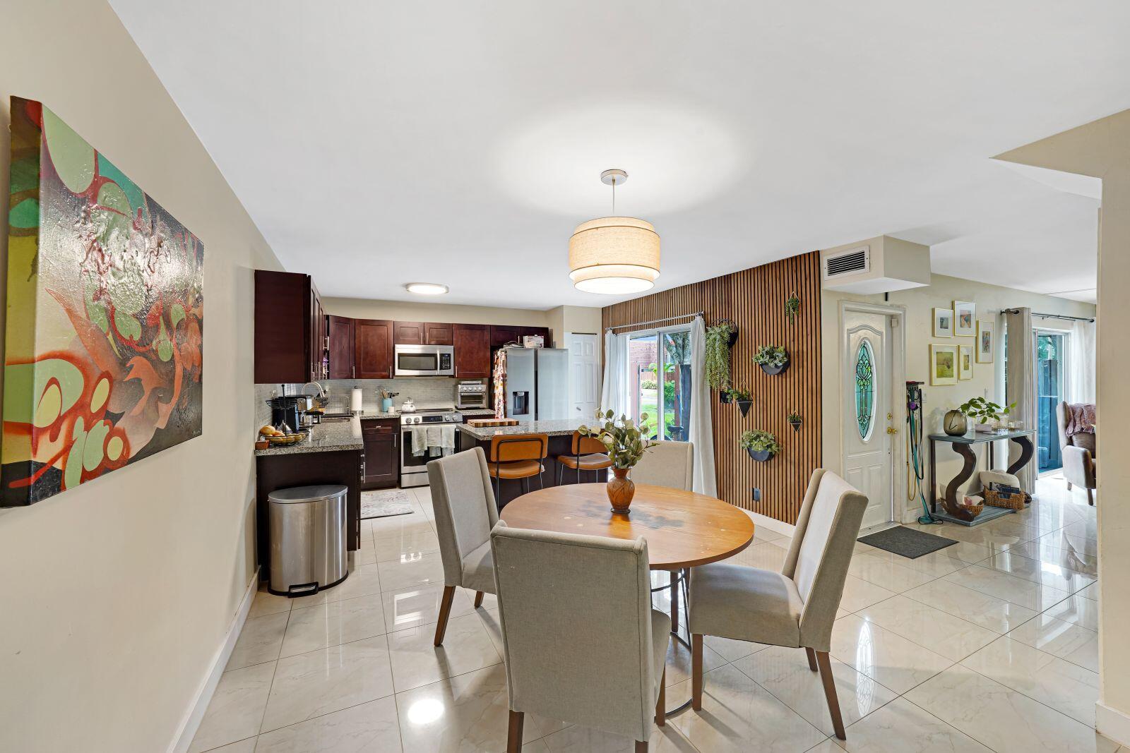 A dining area with a round table sits adjacent to a kitchen with dark cabinetry — 8910 SW 20th Place # 23, Davie FL 33324, DAVIE, FL