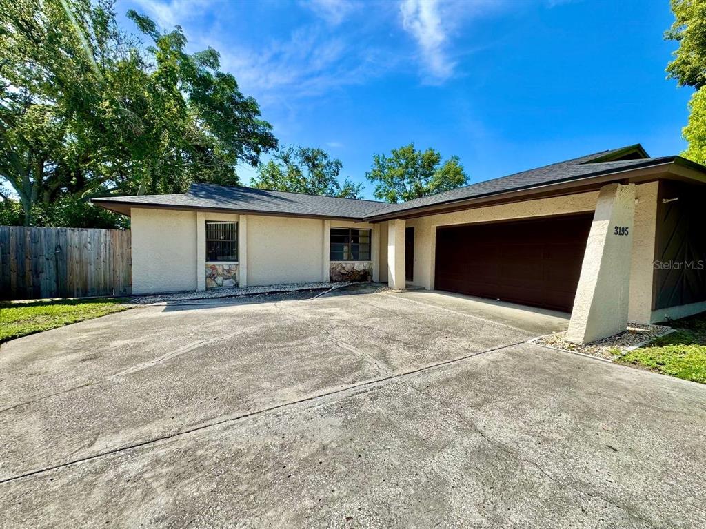 A single-story house with a concrete driveway, a two-car garage, and stone accents — 3195 CHAMBLEE LANE, CLEARWATER, FL